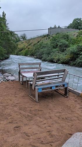 two benches sitting on the side of a river at Дача in Bishkek