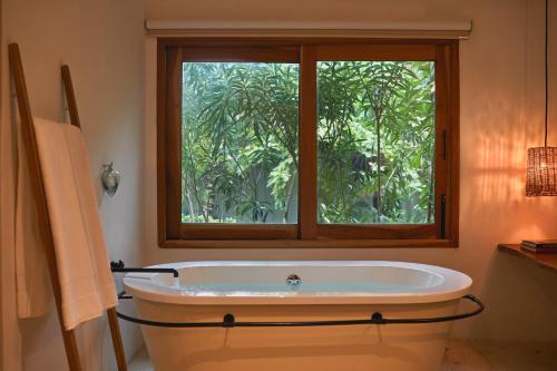 a bath tub in a bathroom with a window at Ser Casasandra Boutique Hotel in Holbox Island