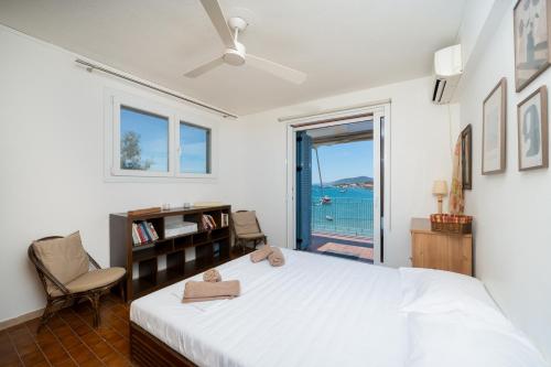 a bedroom with a bed and a chair and a window at KYMA by A&D Properties in Porto Rafti