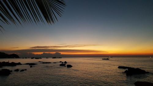 a sunset over the ocean with rocks in the water at Simple Life Cliff View Resort in Koh Tao