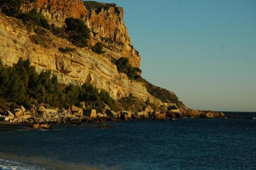 a rocky cliff next to a body of water at Cassis Loc - Chambre Meublée in Cassis