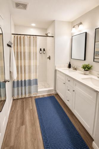 a bathroom with two sinks and a shower and a blue rug at Beachfront Luxe, Ocean Views, Hot tub, Firepit, Sleeps 14 in Bolivar Peninsula