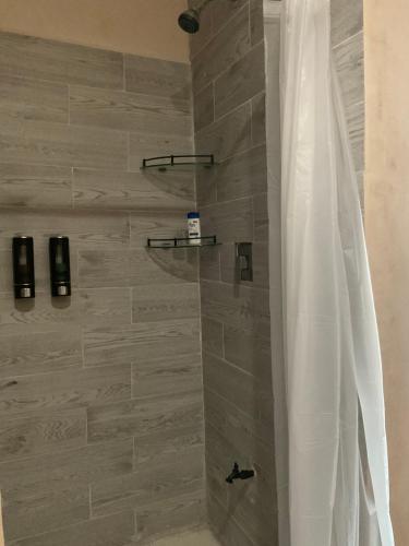 a shower with a white shower curtain in a bathroom at La Casa del Arbol in Chelem