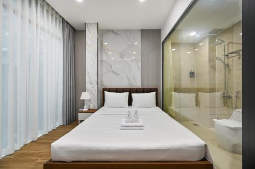 a bedroom with a large white bed and a shower at The Crown Airport Hotel in Ho Chi Minh City