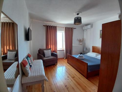 a bedroom with a bed and a chair and a couch at EniGuesthouse in Gjirokastër