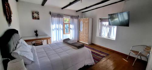 a bedroom with a white bed and a television at The Green Corner Urubamba in Urubamba