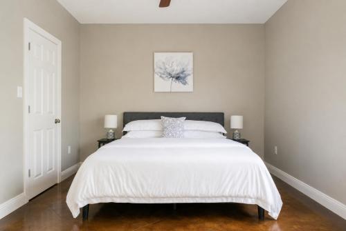 a bedroom with a large white bed with two lamps at Ground Floor, 3BR Sleeps 8, Near Ingalls and Chevron -F- in Moss Point