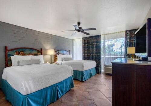 a bedroom with two beds and a flat screen tv at La Posada Lodge & Casitas, an Ascend Collection Hotel in Tucson