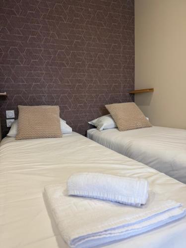 two beds with towels on them in a room at Le Col Getaway Virage 5 in Le Bourg-dʼOisans