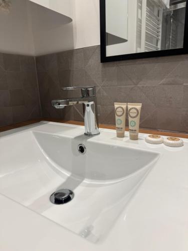a bathroom sink with a faucet and two cups on it at Le Col Getaway Virage 5 in Le Bourg-dʼOisans
