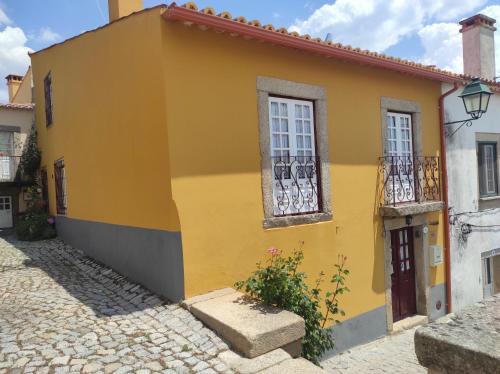 a yellow house with windows on a cobblestone street at Casa do Lagar in Almeida