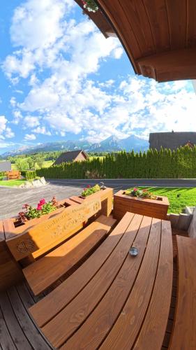 a patio with wooden benches and flowers on it at Apartmány Dominek in Ždiar