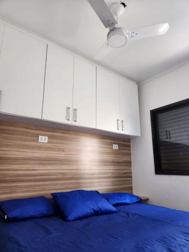a bedroom with a blue bed and white cabinets at Apto Sol Nascente in Mongaguá