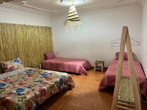 a bedroom with two beds and a chandelier at DAR SANAE SURF in Aourir