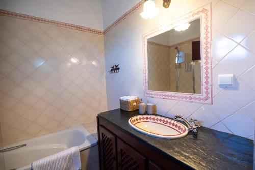 a bathroom with a sink and a mirror and a tub at Horta dos Cismeiros, Monsaraz - Monte Alentejano com Piscina in Monsaraz