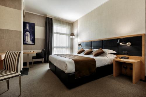 ルーヴォ・ディ・プーリアにあるHotel Pineta Wellness & Spaの大きなベッドとデスクが備わるホテルルームです。