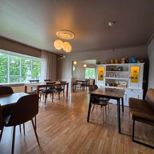 a dining room with tables and chairs and windows at Akureyri Hostel in Akureyri
