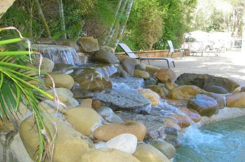 a river with rocks and a waterfall in a yard at Lighthouse Beach Holiday Village in Port Macquarie