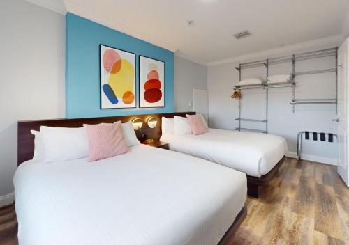 two white beds in a room with blue walls at Nuvo Suites Hotel - Miami Doral in Miami