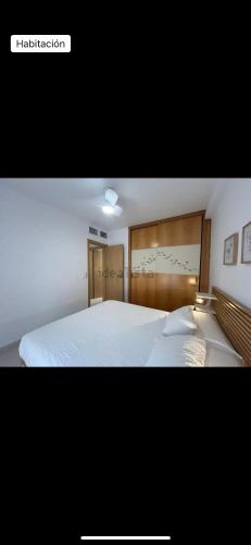 a bedroom with a large white bed with a wooden headboard at Vera dream Las Marinas LAGUNA BEACH in Vera