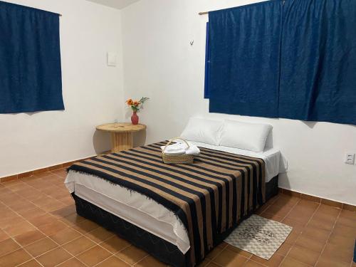 a bed in a room with blue curtains at Pousada Nosso Sonho in Natal