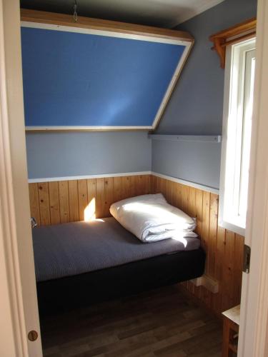 a small bed in a room with a blue wall at Klarälvens Camping in Stöllet