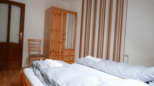 two twin beds in a room with a chair at Paulay Borház és Vendégház in Tokaj