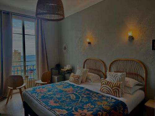 a bedroom with a bed with a view of the ocean at Hôtel Eden - La Baigneuse in Juan-les-Pins