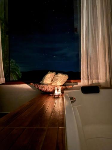a bed with two pillows on a wooden floor with a window at Pousada Belvedere da Serra in Serra do Cipo