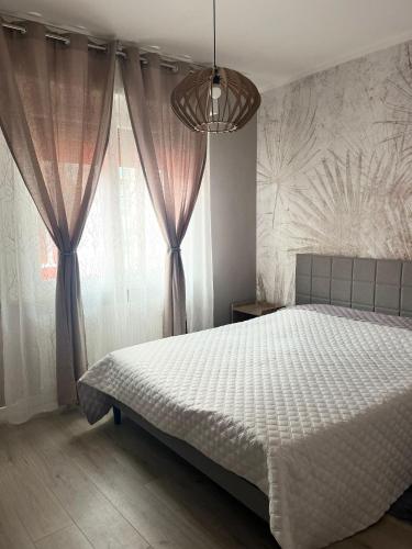 a bedroom with a white bed and a large window at Via Roma Residence in Maniago