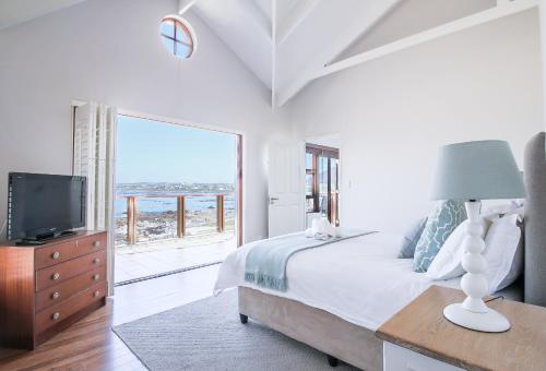 a bedroom with a bed and a tv and a window at Geheim Luxury Seafront in Hermanus