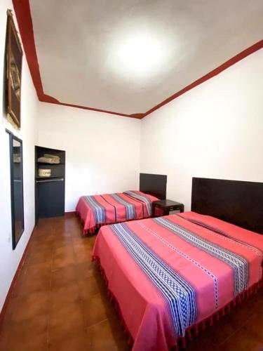 two beds in a room with white walls at Habitación 11 Posada Itzel in Oaxaca City