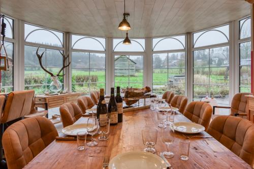 a large dining room with a long wooden table with wine glasses at Chambres Ardennez-vous in Saint-Hubert
