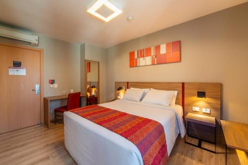 a hotel room with a large bed and a desk at Hotel Laghetto Stilo Higienópolis in Porto Alegre