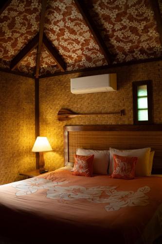 a bedroom with a large bed and a lamp at Rarotonga Beach Bungalows in Rarotonga