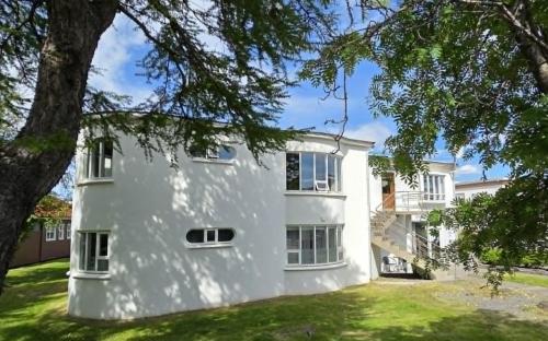 a white house with a tree in front of it at Akureyri Hostel in Akureyri
