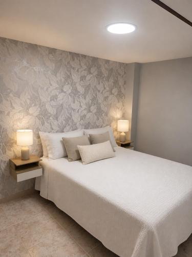 a bedroom with a large white bed with two lamps at Casa Estraviz in A Coruña