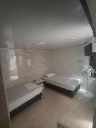a bedroom with two beds and a fan at Posada El Carro Amarillo SAS in Floridablanca