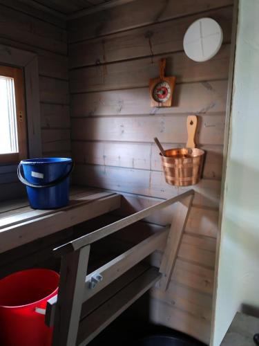 a kitchen with a counter with a bucket and a wooden wall at Metsämökki in Lohja
