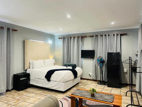 a bedroom with a bed and a table and a couch at De'Lush Oasis in Pretoria