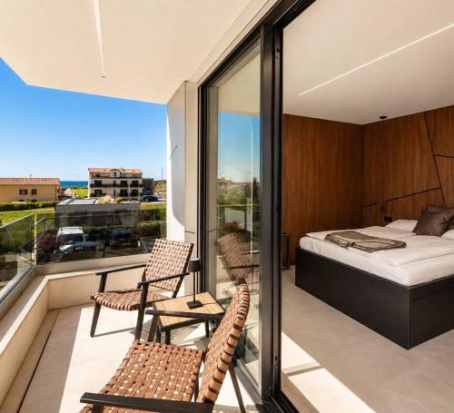 a bedroom with a bed and two chairs on a balcony at Villa9eleven in Novigrad Istria
