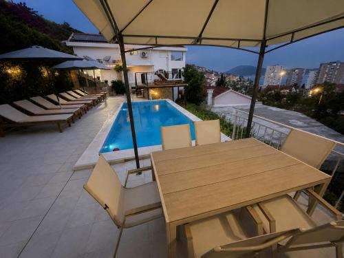 a patio with a table and chairs and a swimming pool at Al Mare Vacation Home in Igalo