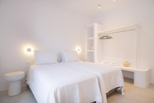 a white bedroom with a white bed and a desk at Villa Serenity Complex in Kampos Paros