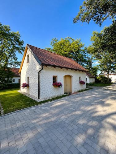 a white building with a brown roof and a driveway at Kellerstöckl Gehringer in Guntersdorf