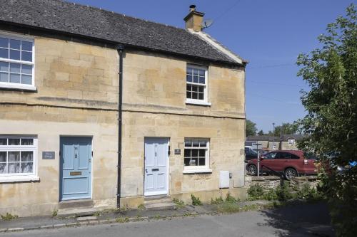 an old stone building with blue doors and a red car at Charming Cotswold Cottage in Central Winchcombe in Winchcombe