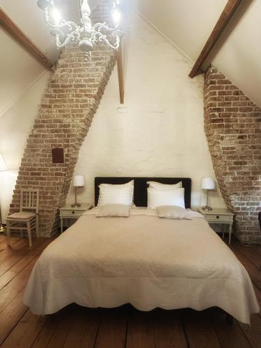 a bedroom with a large bed and a brick wall at B&B In Bruges in Bruges