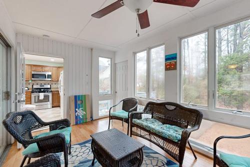 a living room with chairs and a table and windows at Teal Haven in Ocean Pines