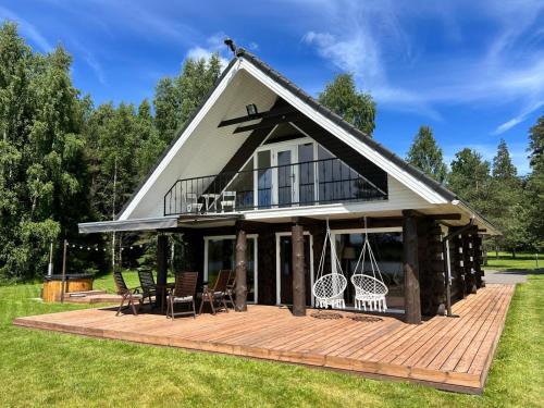 a house with a large deck with chairs on it at Mäeküla Järve Palkmaja in Viljandi