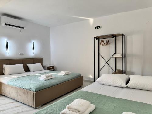 two beds in a white room with towels on them at Siblings by the Sea in Skala Marion