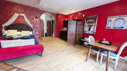 a bedroom with red walls and a bed and a table at Le Rubis - Votre cocon d'orient in Calais
